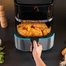 Cargar imagen en el visor de la galería, Una mano sacando la cesta de la freidora de aire Cecofry Full Inox 5500 Pro, llena de pollo frito crujiente.
